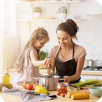 Mutter und Tochter kochen gemeinsam in einer hellen Küche, rühren Gemüse in einem Topf – gesunde Ernährung für Kinder spielerisch erleben.