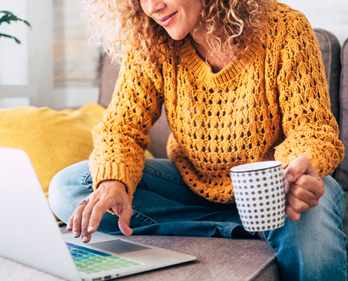 Junge Frau nimmt lächelnd an einer Online-Infoveranstaltung der EHiP teil, sitzt mit Laptop und Headset in modernem, hellen Raum.